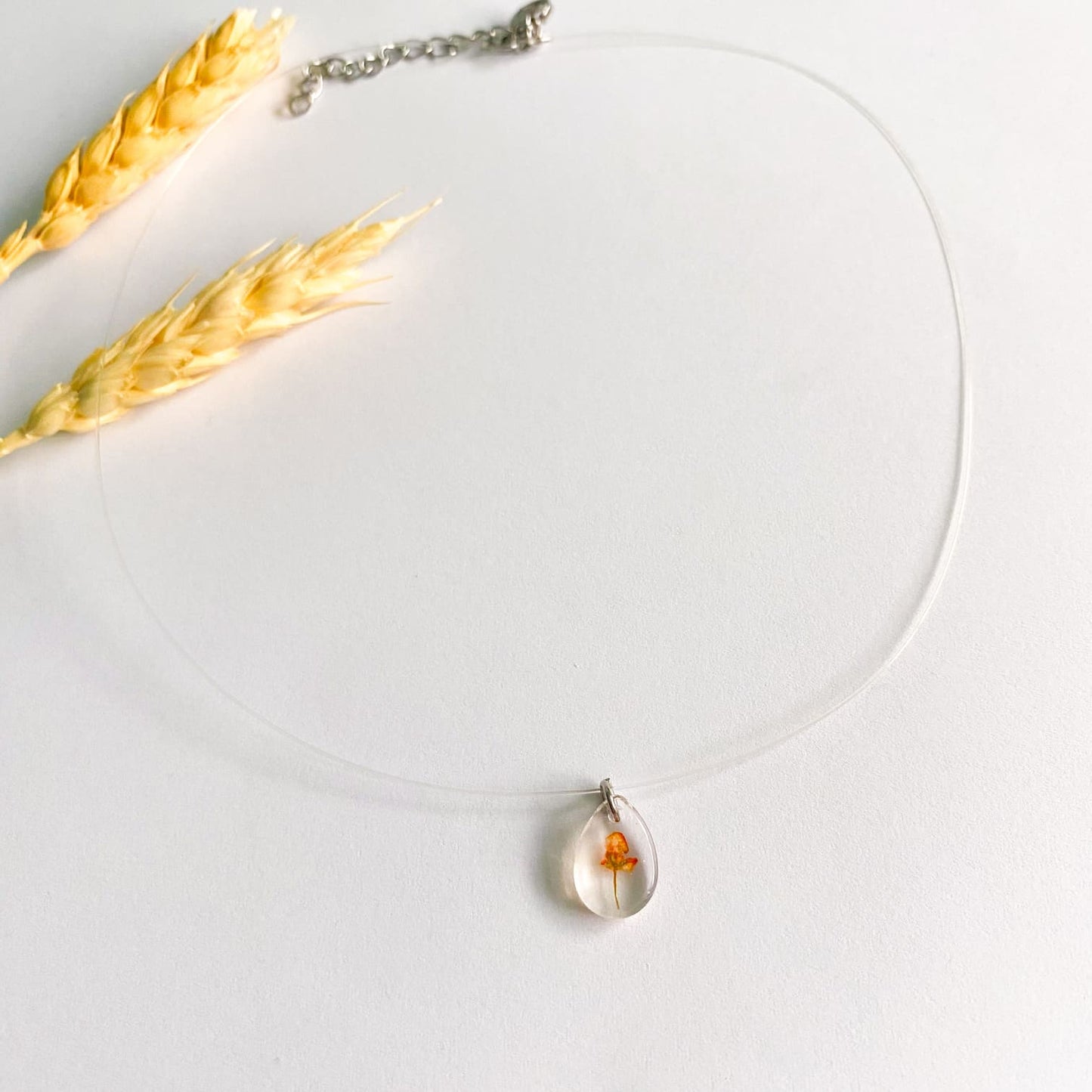 Lănțișor pe fir transparent cu floare portocalie oval 2