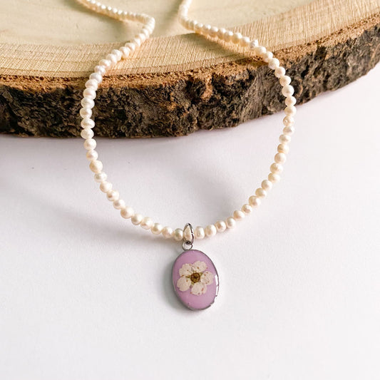 Colier cu perle de cultură, fundal roz și floare albă