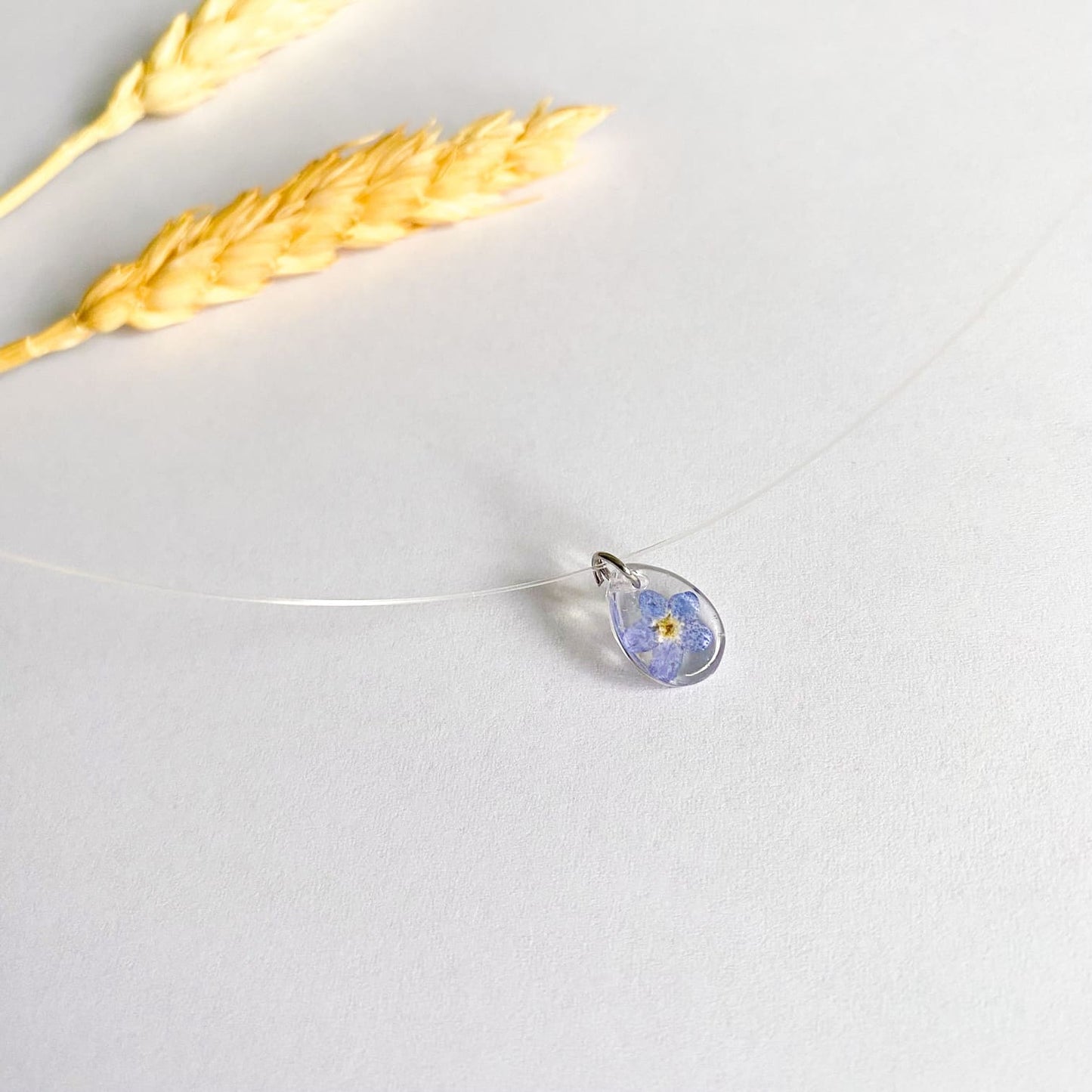 Lănțișor pe fir transparent cu floare de Nu-mă-uita oval