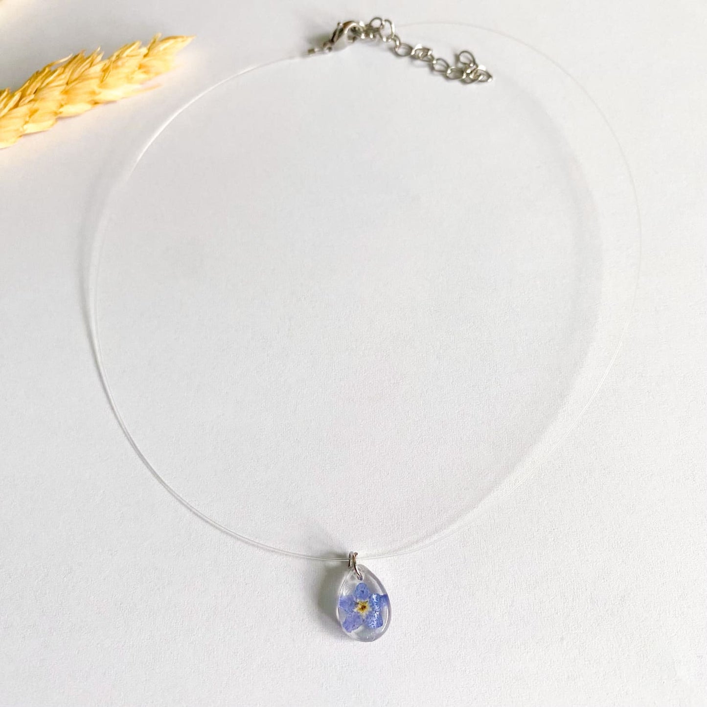 Lănțișor pe fir transparent cu floare de Nu-mă-uita oval